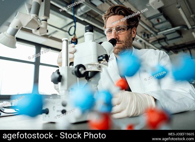 Mature scientist examining with microscope in laboratory