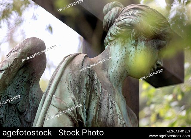 Weathered statue of angel standing outdoors