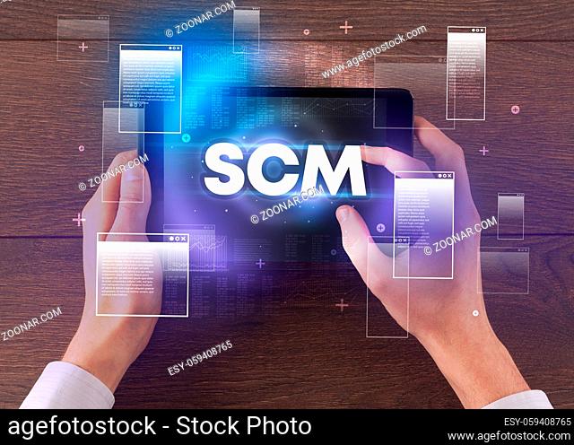 Close-up of a hand holding tablet with SCM abbreviation, modern technology concept