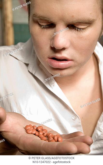 Young man looking at pills in his hand
