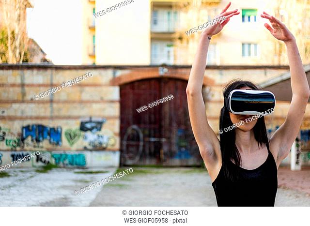 Italy, Verona, Ballerina dancing in the city wearing VR glasses