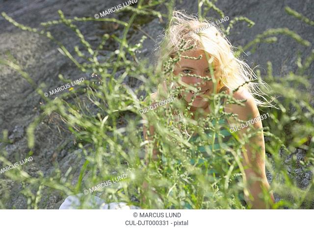 Young woman hiding behind bush