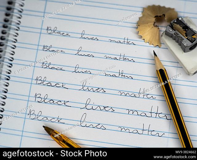 A calligraphic school notebook with pencil, rubber, pencil sharpener and pens show the slogan Black LIves Matter