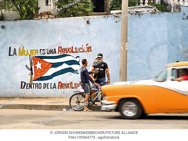 A wall on the roadside in Cienfuegos is painted with the Cuban national flag and a revolutionary slogan. (26 November 2017) | usage worldwide