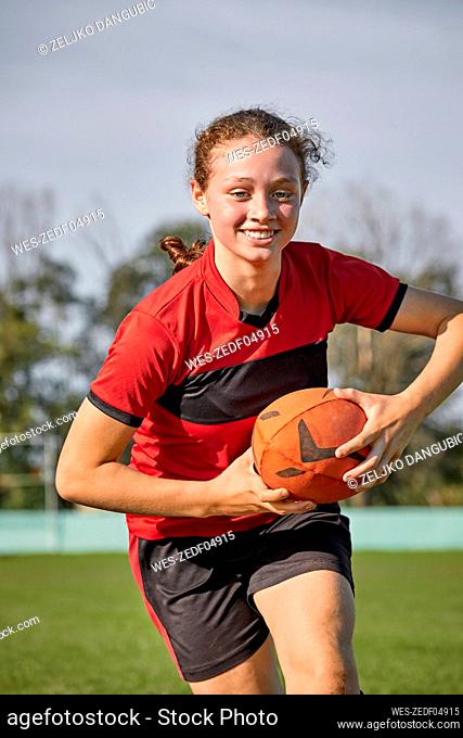 Happy girl with rugby ball practicing on sunny day