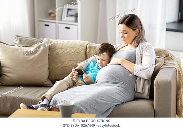 pregnant mother and son with smartphone at home