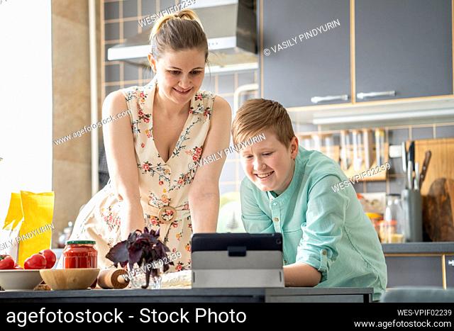 Mother and son using digital tablet in the kitchen