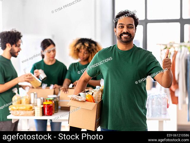 male volunteer with food in box showing thumbs up