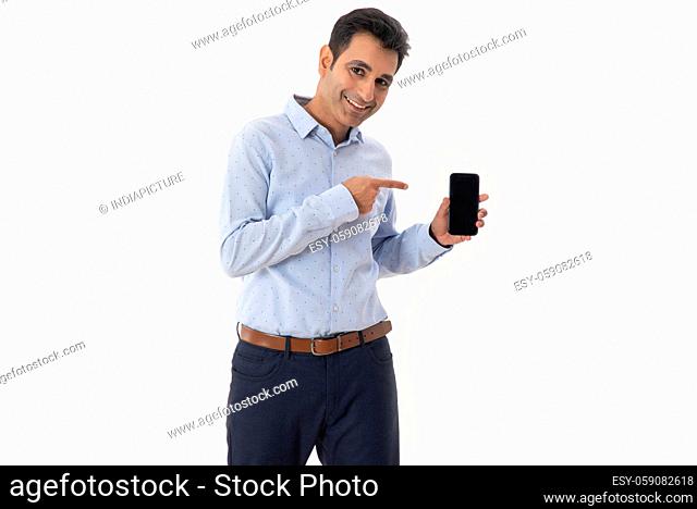 A CORPORATE MAN STANDING AND POINTING TOWARDS MOBILE PHONE IN HAND