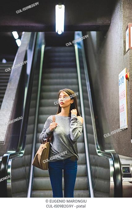 Young woman moving down city escalator