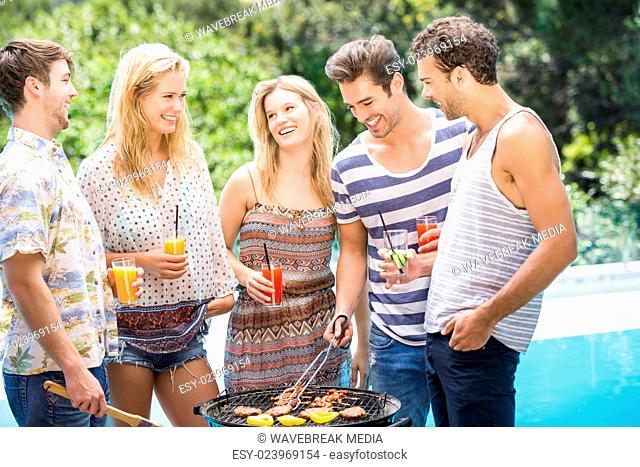 Group of friends preparing barbecue near pool