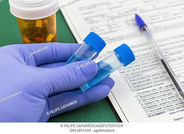 Scientist with blue latex gloves holds vials of test in laboratory for analysis