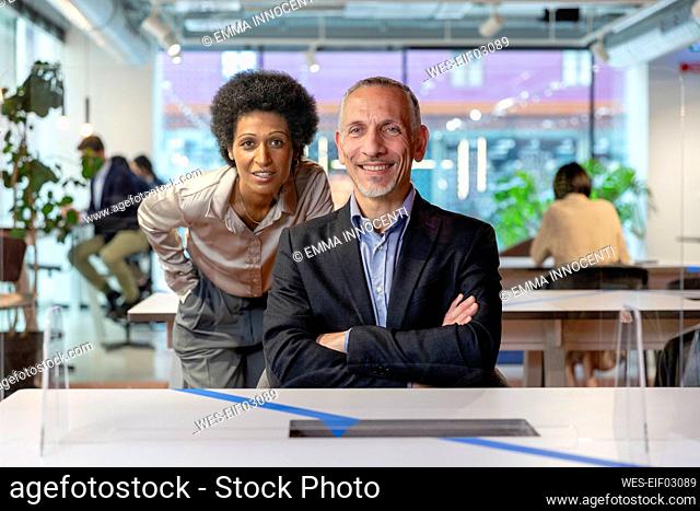 Smiling colleagues seen through transparent glass in coworking space