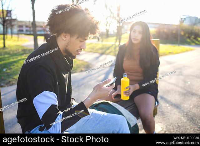 Sportive young couple taking a break sitting on a bench