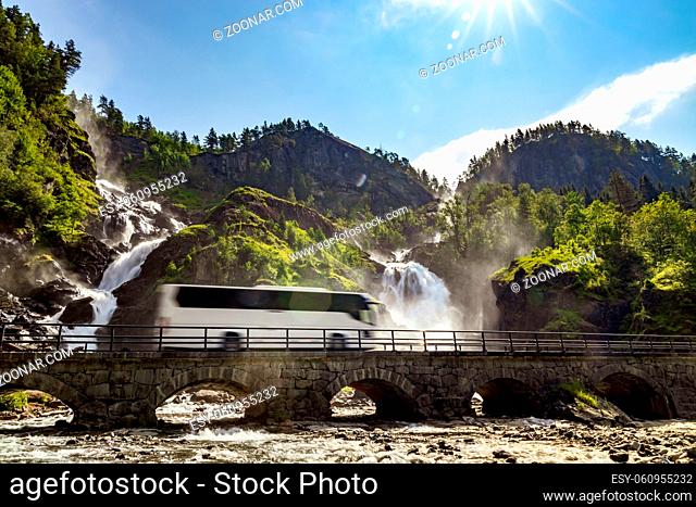Tourist bus traveling on the road Latefossen Waterfall Odda Norway. Latefoss is a powerful, twin waterfall