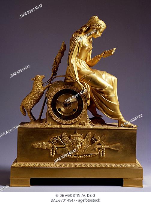 Mantel clock with casing surmounted by a figure of a young girl reading a book and holding a lamb with a ribbon, and base with trophies, gilt bronze