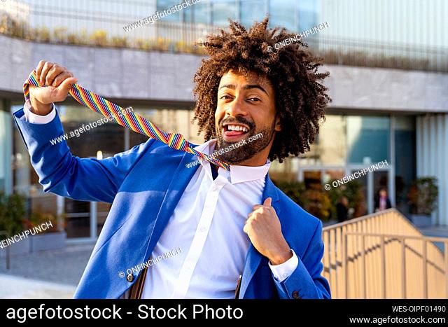 Playful businessman pulling necktie in front of building