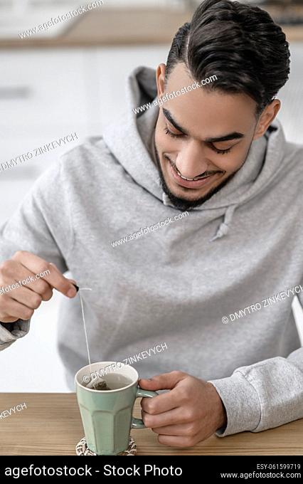Morning at home. A man in a grey hoodie having tea