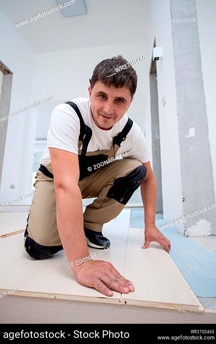 professional carpenter installing new laminated wooden floor in a unfinished apartment