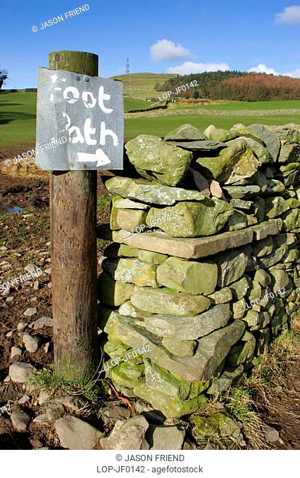 England, Cumbria, Ulverston, Foot path sign and dry stone wall on route to Old Hall Farm on the Cumbria Way