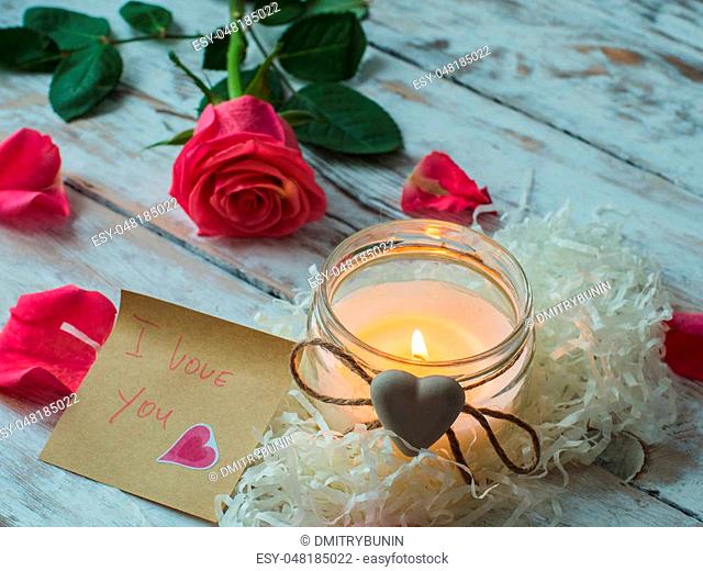 Burning candle and rose petals on vintage wooden table. Valentine's Day and Mother's Day background
