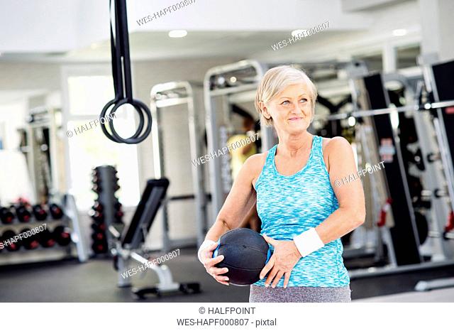 Mature woman holding ball in fitness gym