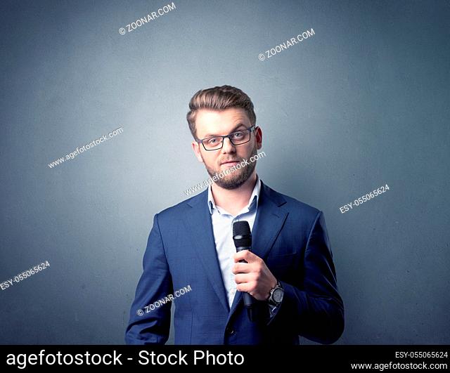 Businessman speaking into microphone with blue background