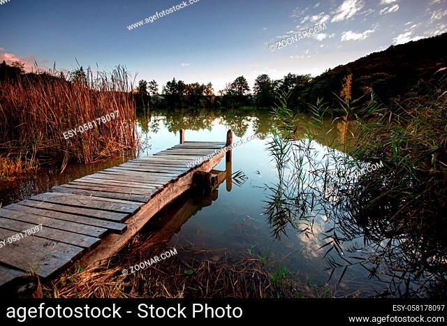 Place near lake to settle down your thoughts. Wooden pier on a lake near autumn forest. Mental health concept