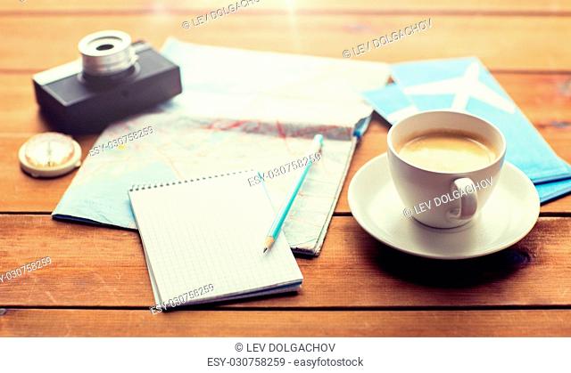 vacation, tourism, travel and objects concept - close up of blank notepad with map, coffee and airplane tickets