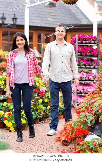 Couple holding hands walking through garden center