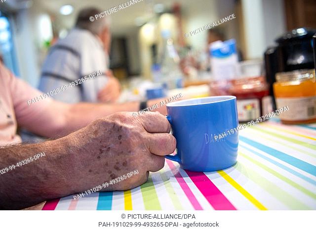 29 October 2019, Baden-Wuerttemberg, Frickenhausen: A man sits in a senior group for people with disabilities with a cup of coffee at breakfast