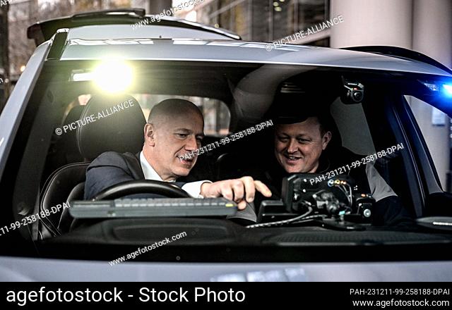 11 December 2023, Berlin: Kai Wegner (l, CDU), Berlin's governing mayor, is shown a networked police vehicle of the future by Adrian Parsons