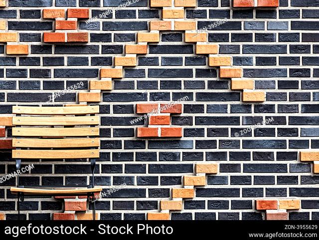 Wand aus Ziegelsteinen mit Holzstuhl am Bildrand