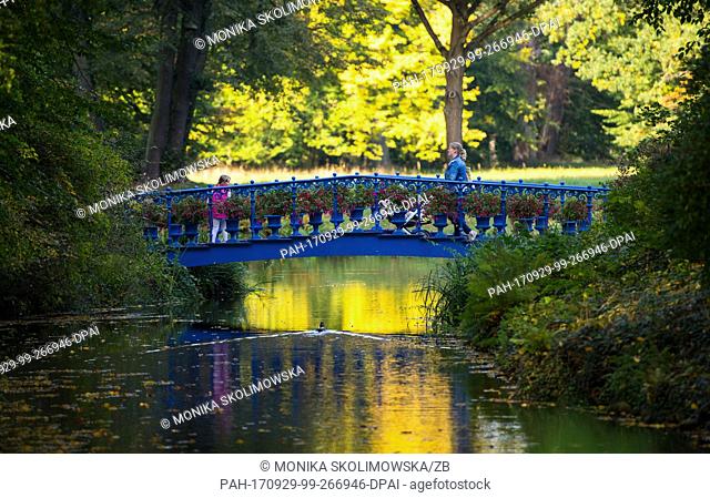 Passerbys cross a bridge in the Fuerst-Pueckler-Park in Bad Muskau, Germany, 29 September 2017. Photo: Monika Skolimowska/dpa-Zentralbild/ZB