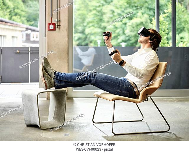 Man wearing VR glasses sitting on chair
