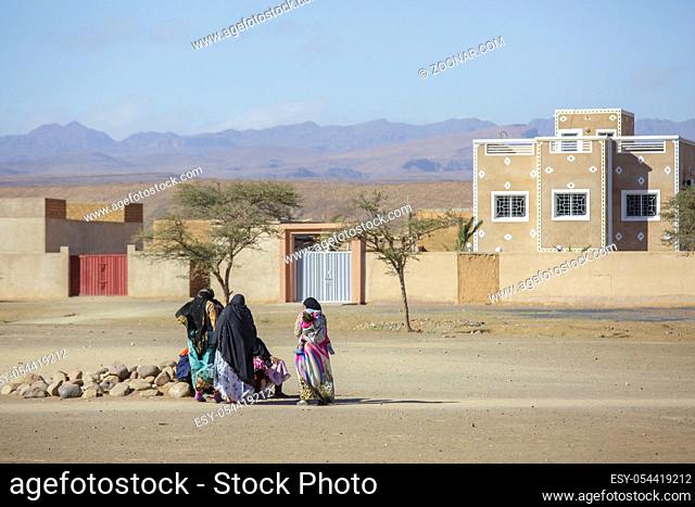 Tinghir, Morocco - February 27, 2016: Women sitting outside sand house on rocks talking to each other in Tinghur city of southern Morocco