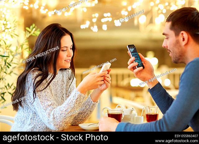 happy couple with smartphones drinking tea at cafe