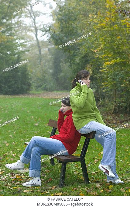 Two teenagers, twin sisters, calling with mobile phones
