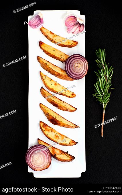 Baked potatoes and red lus with rosemary and garlic on a white rectangular plate