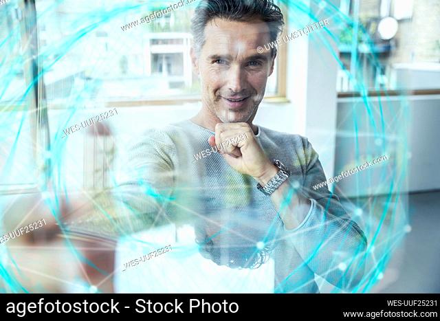 Smiling businessman with hand on chin seen through futuristic sphere at office