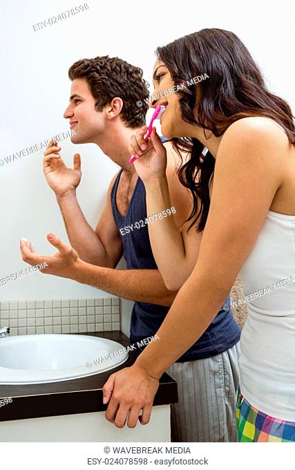 Couple in bathroom applying cream and brushing teeth