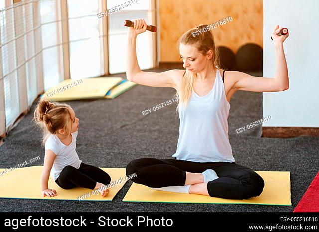 Mom and daughter together perform different exercises in the gym