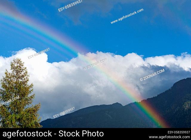 rainbow in mountain landscape with blue sky and white clouds and copy space
