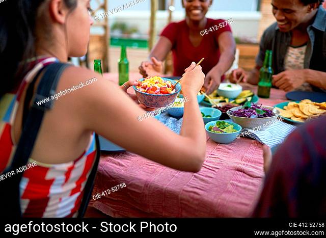 Young friends eating tacos at patio table