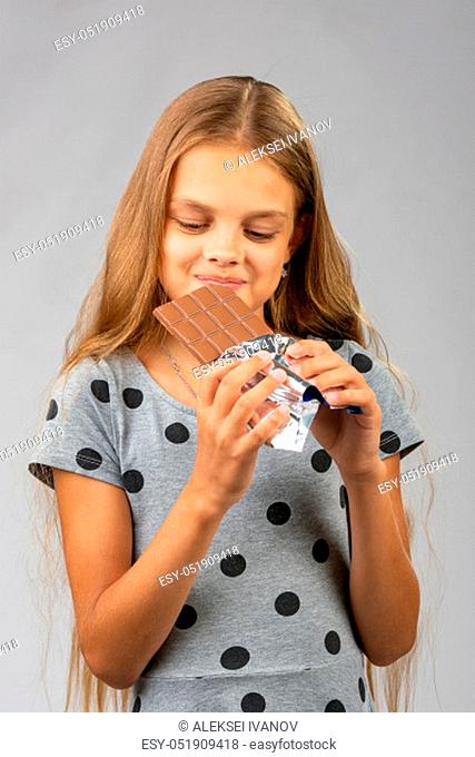 The ten-year-old girl joyfully looks at a chocolate bar