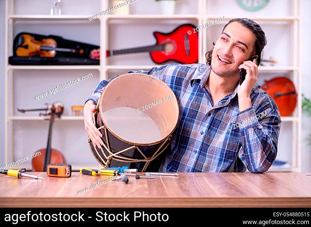 Young handsome repairman repairing drum
