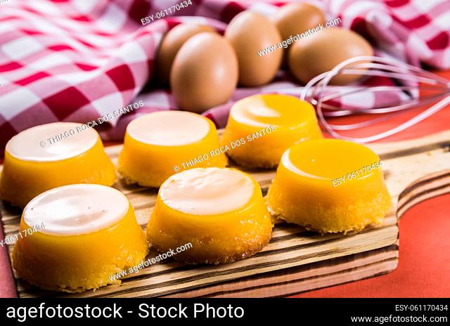 Delicious Quindins on wooden board, traditional Brazilian dessert made with egg yolk, sugar and coconut
