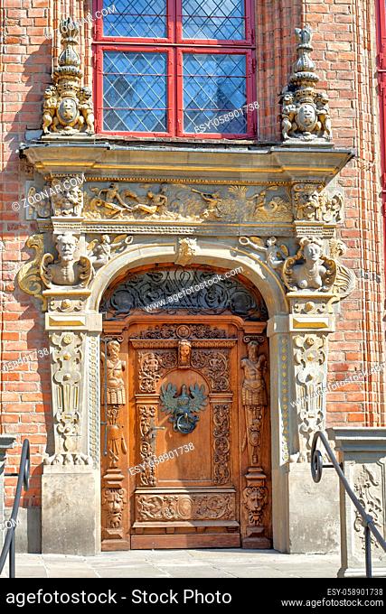 Richly decorated wooden door and entamblature of one of Gdansk Old Town historic buildings, Poland