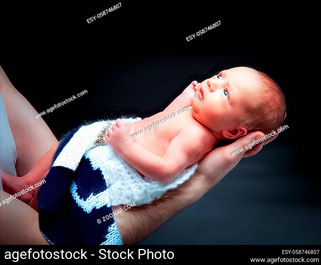 Tiny newborn baby boy on the father's hand