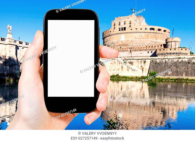 travel concept - tourist photographs Holy Angel Castle (Castel Sant Angelo) in Rome city on smartphone with cut out screen with blank place for advertising in...